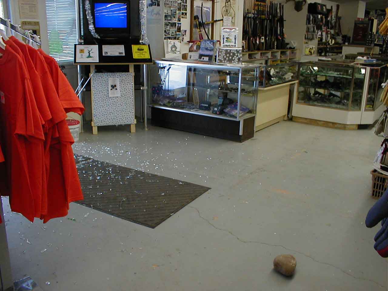 Interior shot of the store with a rock used to break the glass left behind and broken glass on the floor