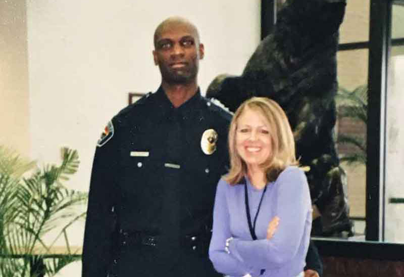Mike stands with his arm around his wife, Stacy, in a lobby in front of a statue of a bear