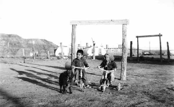 Historic image of two young children on bicycles with a dog