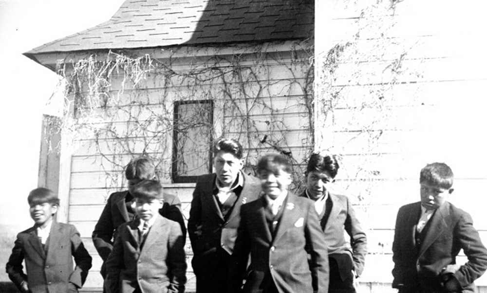 Historic image of boys in suits next to a house