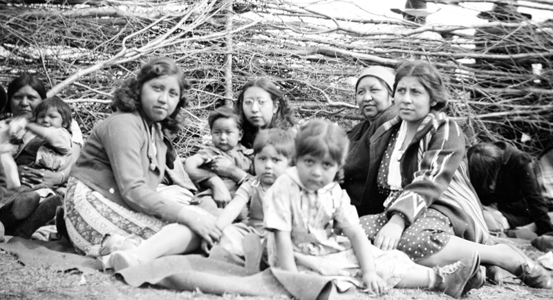 Historic image of young children sitting on the ground outside